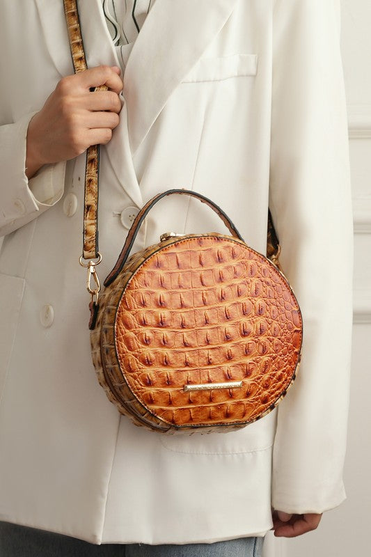 The MKF Collection Ynnari Croc-Embossed Round Crossbody Bag by Mia K. features a stylish croc-embossed pattern and measures 7.87" in length and height, with a 3.14" width. It includes elegant hardware, a secure zipper closure, and an adjustable shoulder strap for comfortable, customizable wear. This bag combines fashion and function, making it a perfect accessory for any occasion.